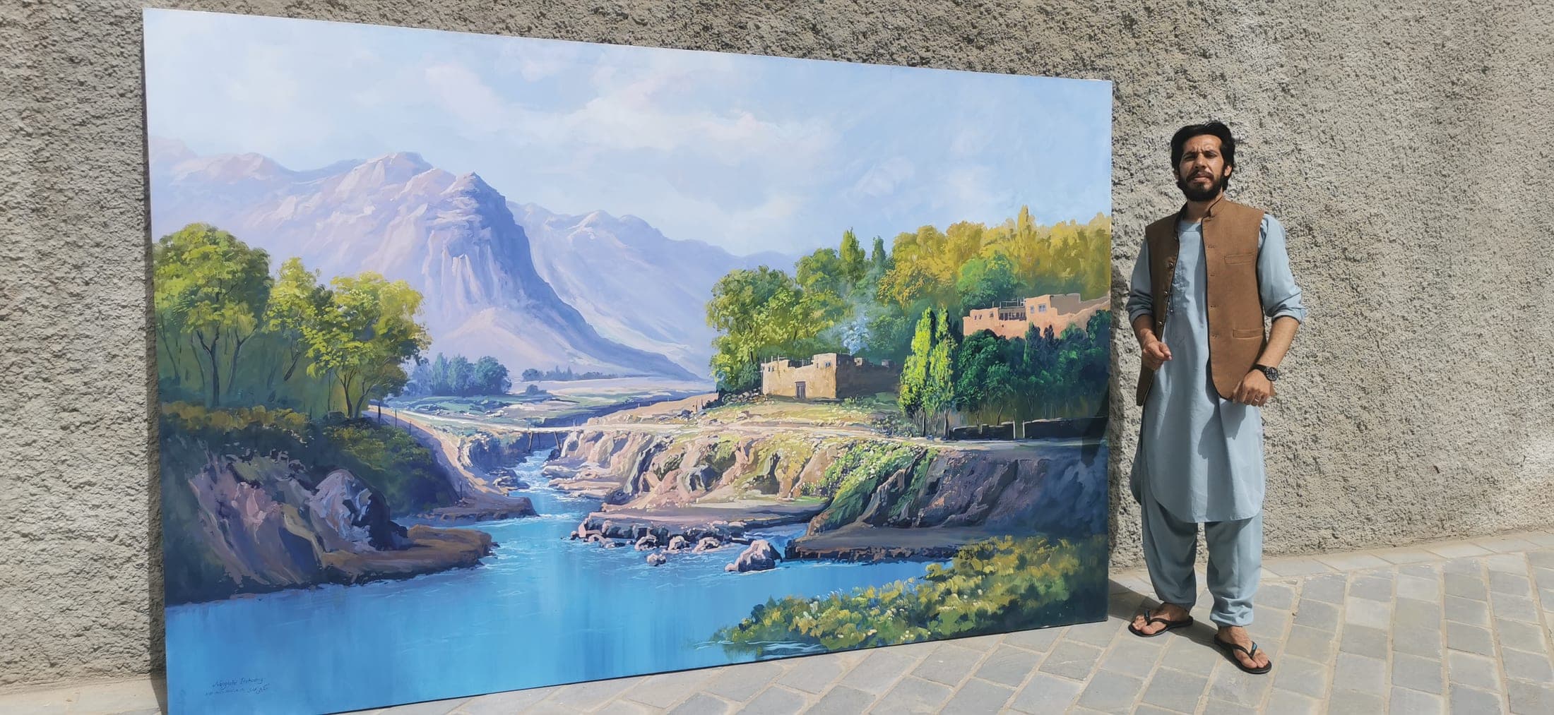 A large river landscape canvas displayed outdoors beside the artist
